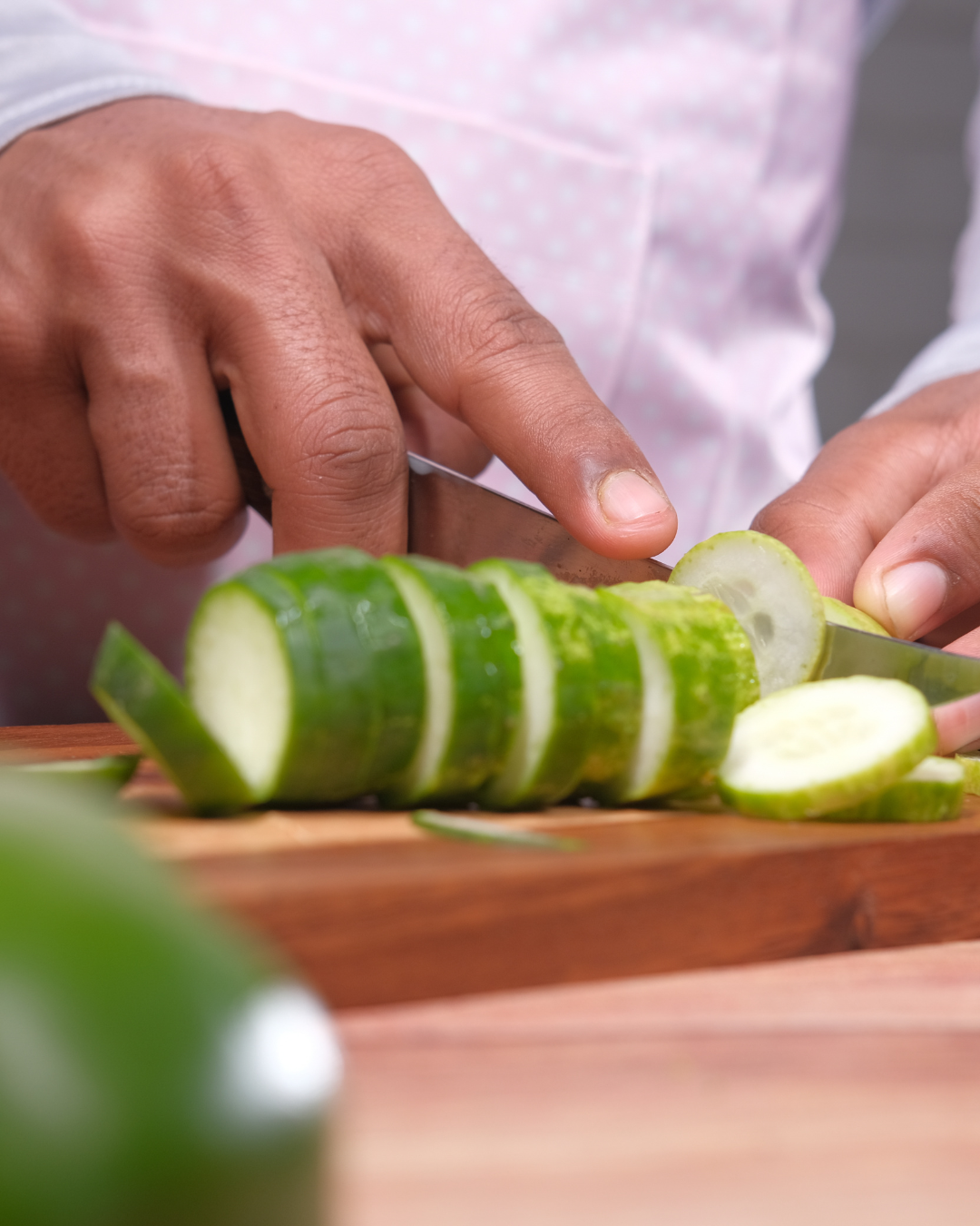 Photo of man's hands chopping a cucumber